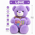 Purple plush teddy bear with a heart-shaped pillow reading 'LOVE' in colorful letters, shown on a white background with product features and dimensions listed. The bear wears a brown gingham bow tie and has embroidered facial details.